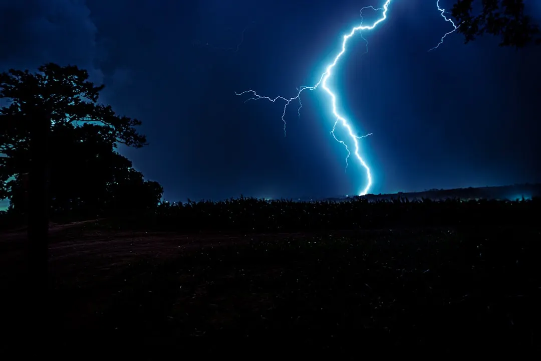 Ein Blitz schlägt nachts in eine dunkle Landschaft ein