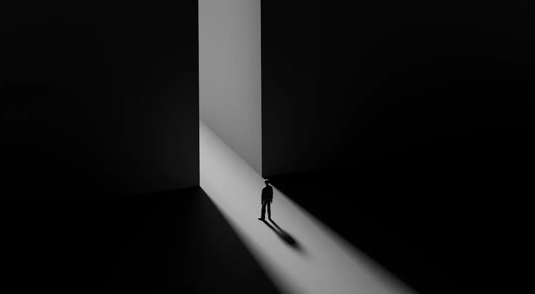 Eine Silhouette steht im hellen Lichtspalt einer Tür im Dunkeln