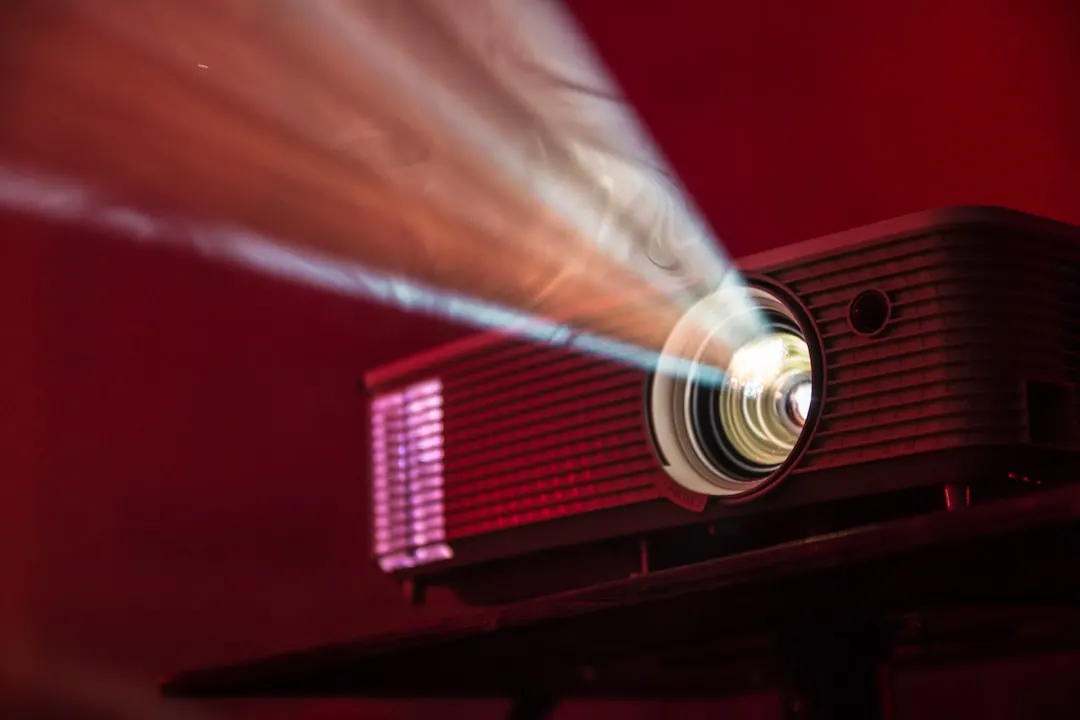 Ein Projektor wirft seinen Lichtstrahl in einen dunklen, rot beleuchteten Raum