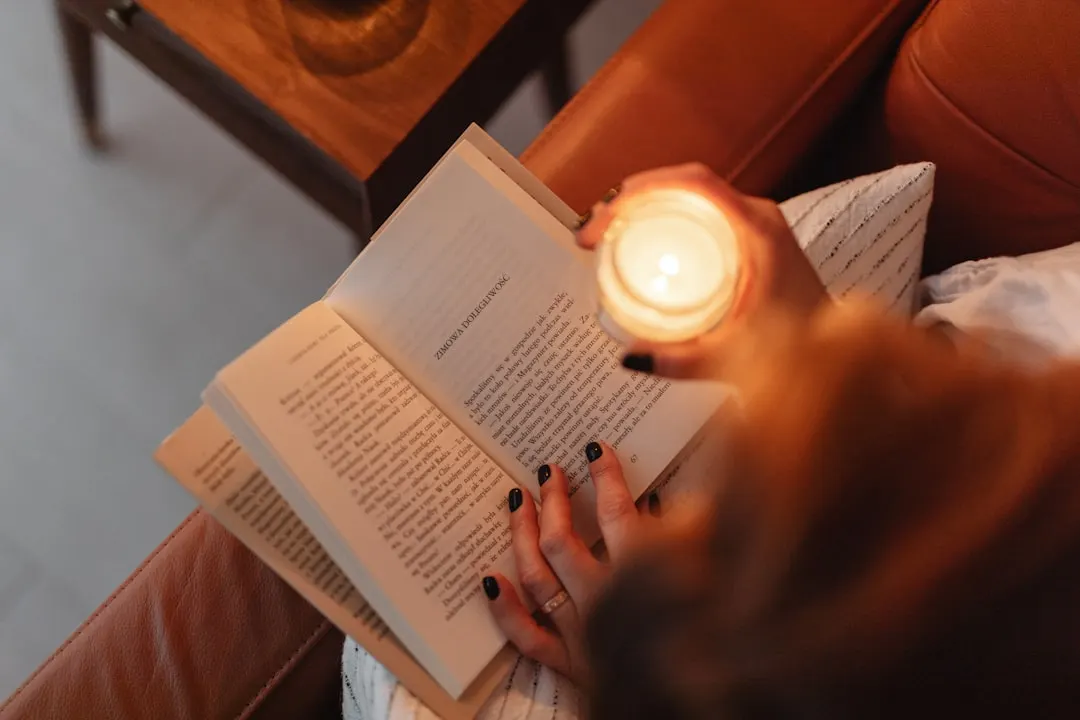 Eine Frau versinkt im Schein einer Kerze in ihr Buch