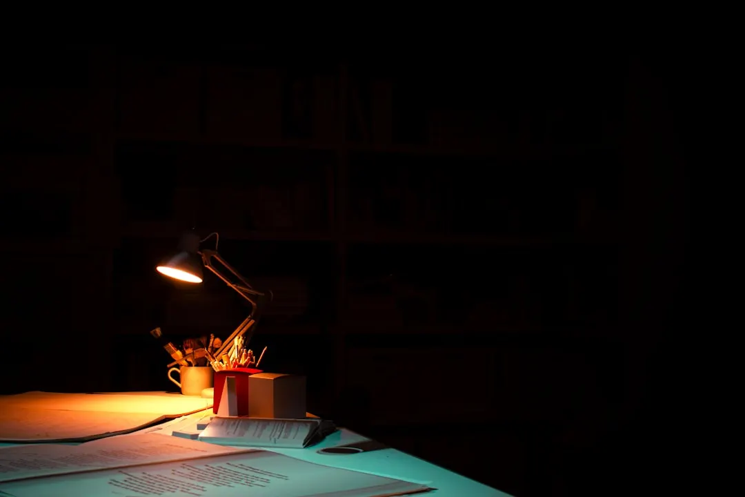 Ein Schreibtisch im Dunkeln, nur von einer warmen Lampe erhellt
