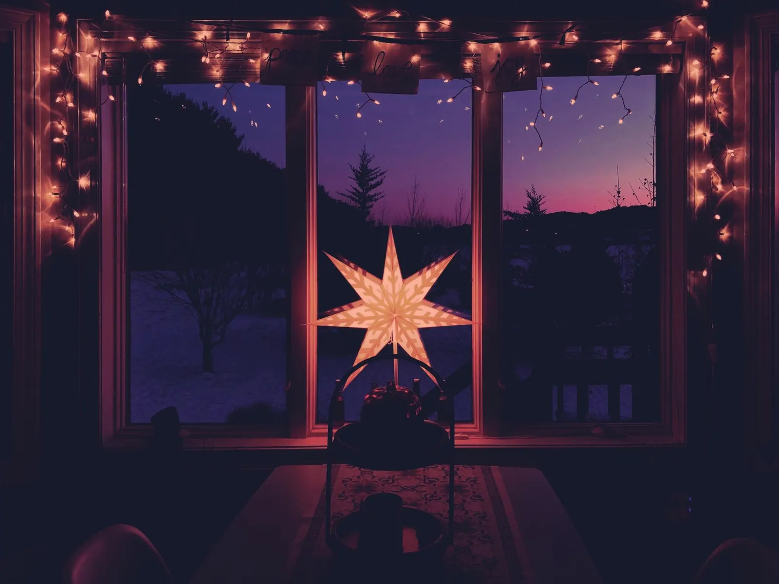 Ein beleuchteter Papierstern am winterlichen Fenster in der Abenddämmerung